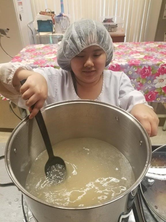 A student from the college preparation program stirs pasta in boiling water to make macaroni and cheese.