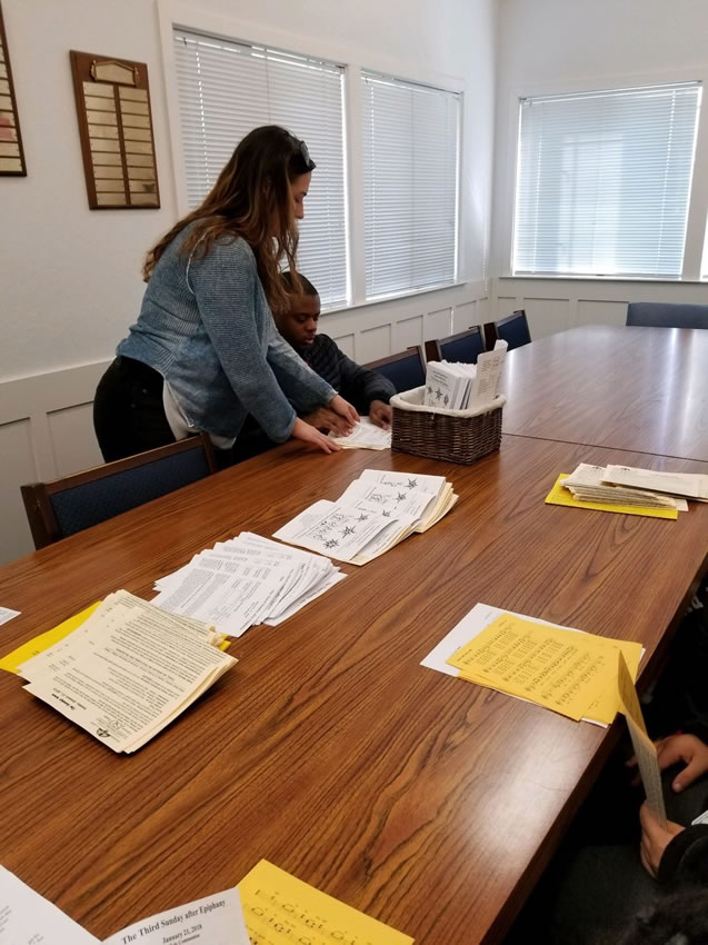 A  teacher working with a student on collating paper.