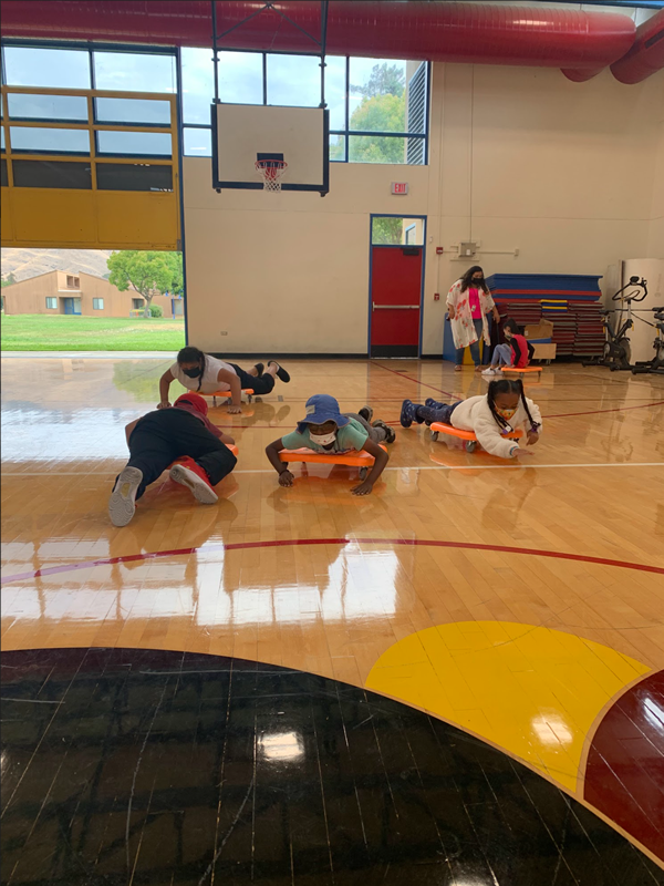 Four students are on their stomachs with their arms on the ground.