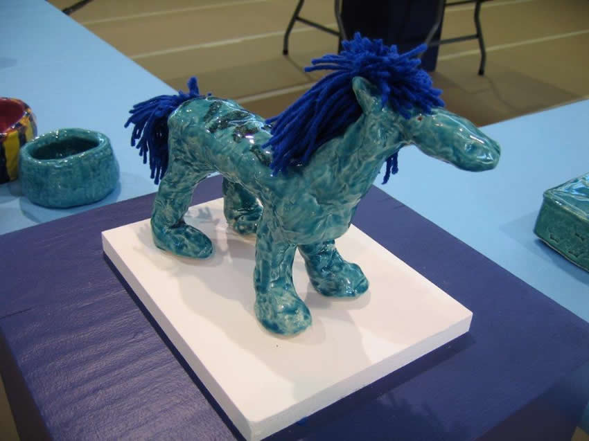 Blue ceramic horse with blue yarn for mane and tail.