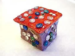 Ceramic cube with purple sides and red top, adorned with buttons.