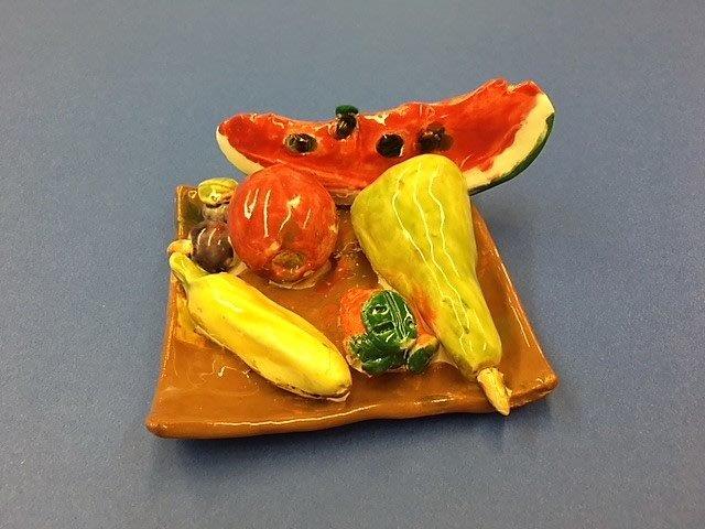 Ceramic of watermelon, banana, apple and other fruit in a square fruit dish.