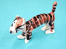 Ceramic tiger, standing on a light blue surface.