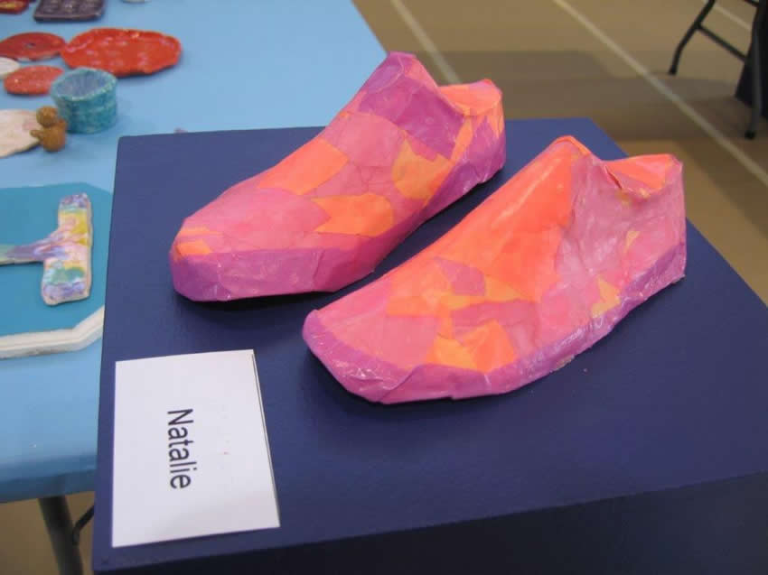 Paper mache shoes with multiple shades of pink.