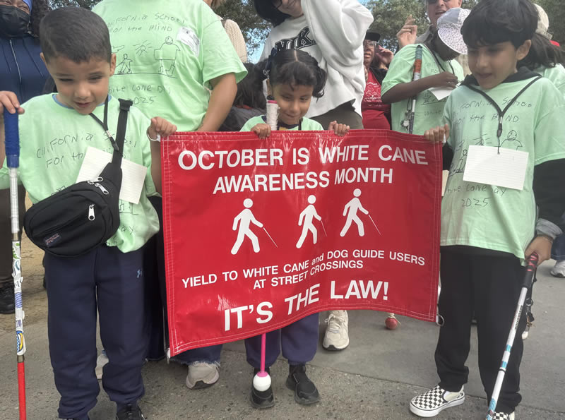 Three csb students in White Cane Day t-shirts, holding white canes and the October is White Cane Awareness Month banner.