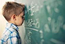 Boy standing with his nose against a chalkboard.