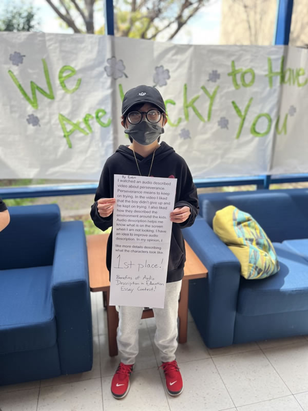 A student holding a printout of his essay winning first place.