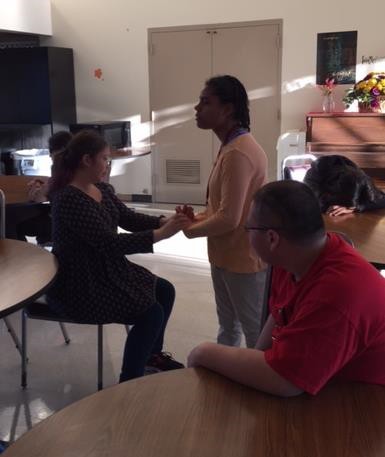 Instructor standing in front of a seated student, holding the students hands out in front.