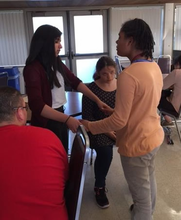 Instructor standing face to face with a student, holding the student's hands slightly in front.