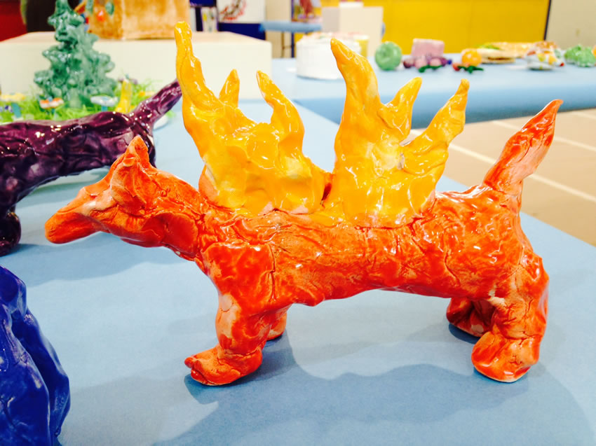 Ceramic sculpture of a red dog with orange flames.